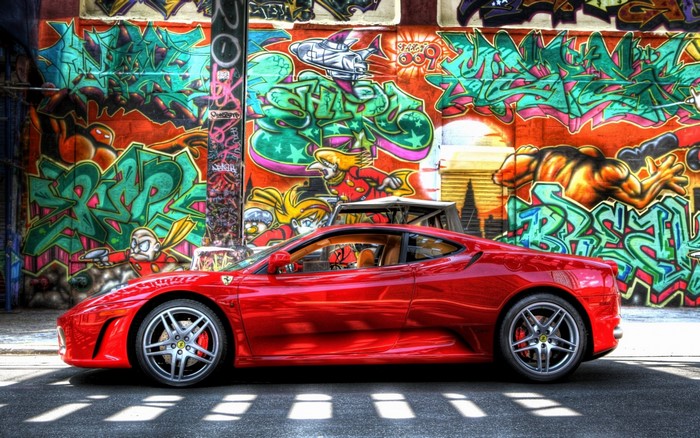 Red Ferrari F430 parked in front of graffiti wall