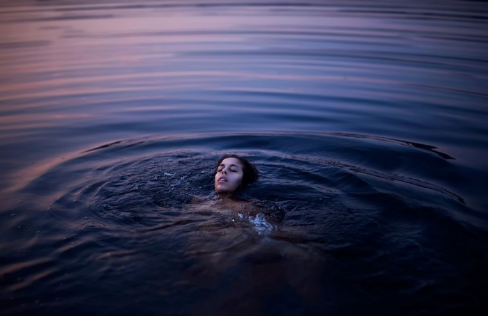Woman swimming in dark water at sunset
