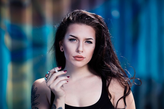 Woman with tattoos and piercings smoking a cigarette