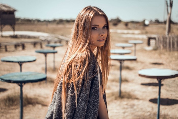Woman with long brown hair wearing a gray cardigan outdoors