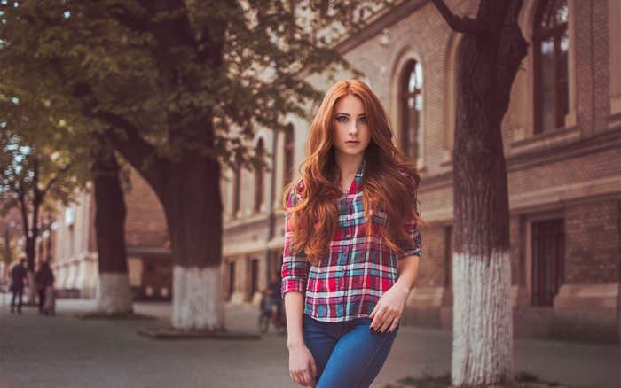 Redhead woman in plaid shirt and jeans on street