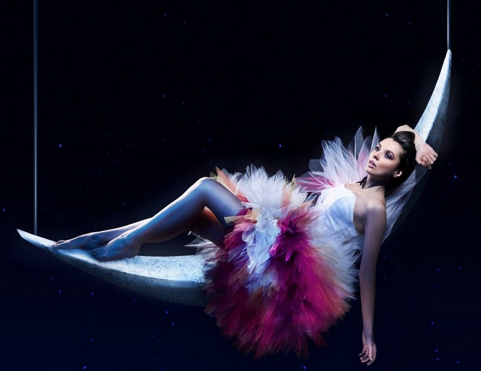 Woman in tutu on crescent moon against starry sky