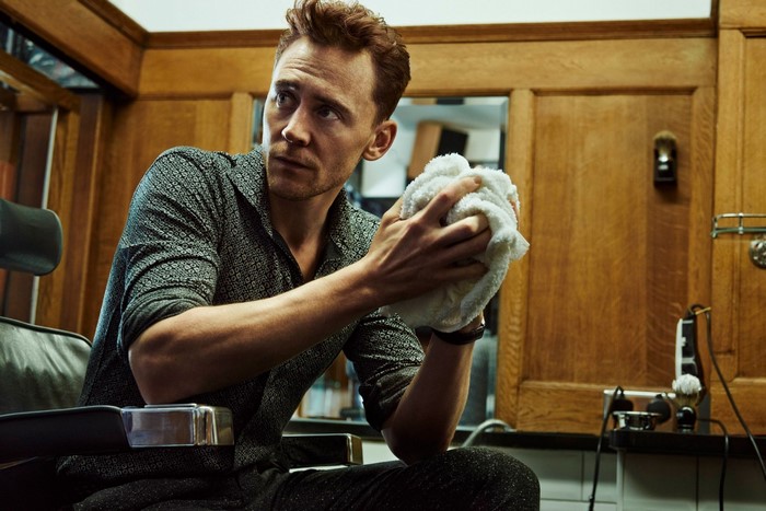Tom Hiddleston sitting in a barber chair holding a towel