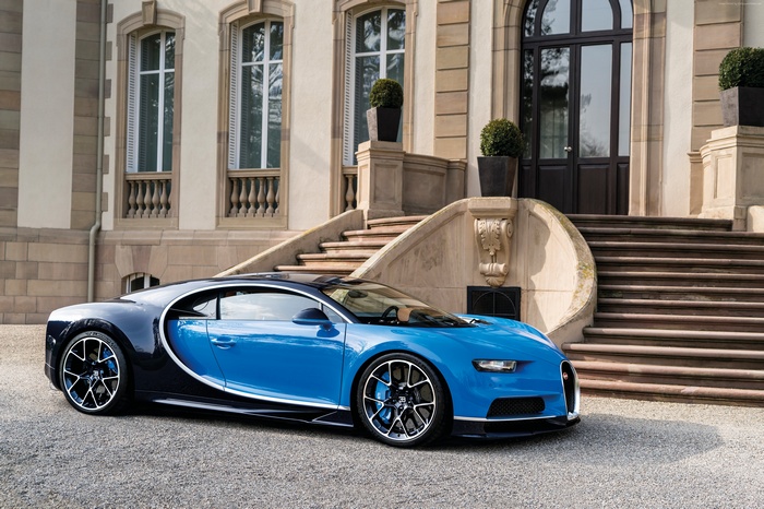 Blue Bugatti Chiron hypercar parked in front of a mansion