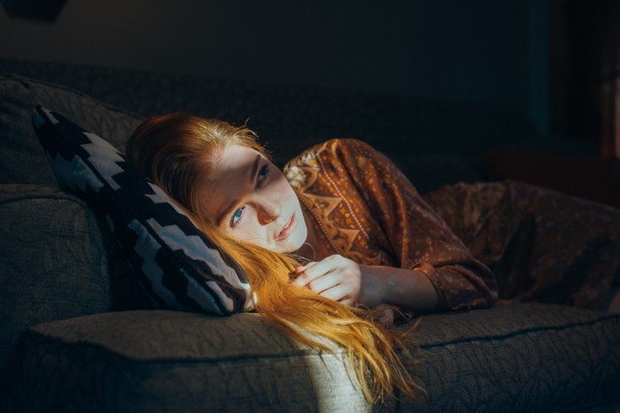 Redhead woman with blue eyes lying on a couch