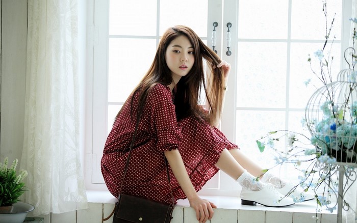 Asian woman in red patterned dress by window