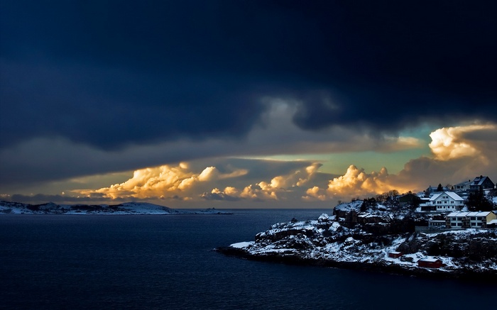 Snowy coastal village under dramatic stormy clouds