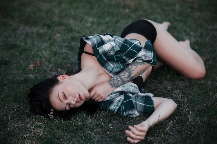 Woman lying on grass with tattoos