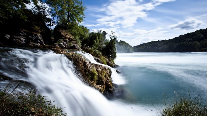 Waterfall flowing over rocks into a wide river
