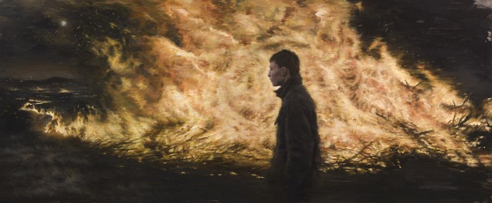 Person standing in front of a large bonfire at night