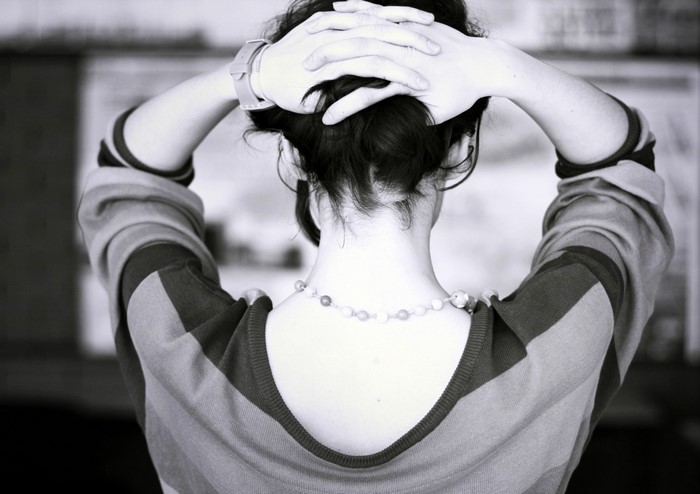 Woman with hands on head wearing striped sweater and necklace