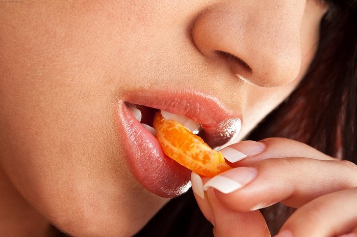 Close up of woman eating a tangerine slice