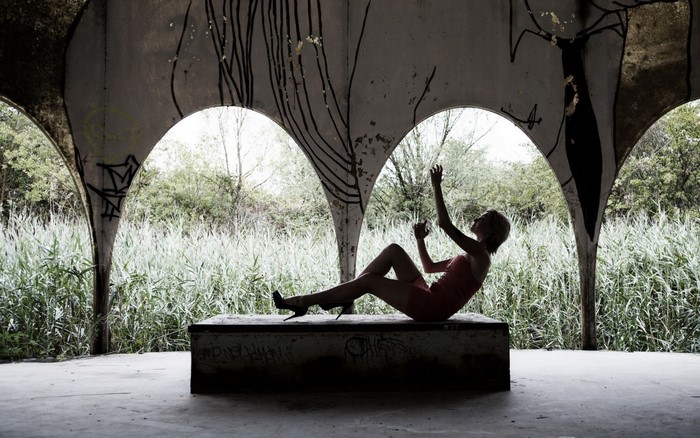 Woman posing on a concrete structure in an abandoned building