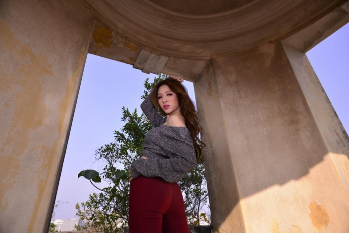 Woman in off-the-shoulder top and red pants posing