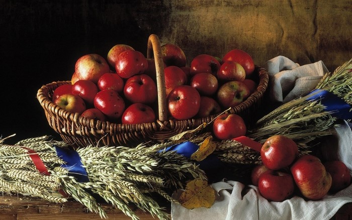 Basket of red apples with wheat and autumn leaves