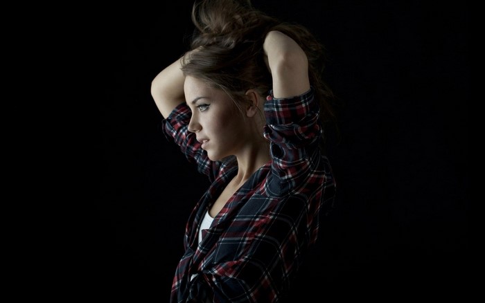 Woman with arms up in plaid shirt