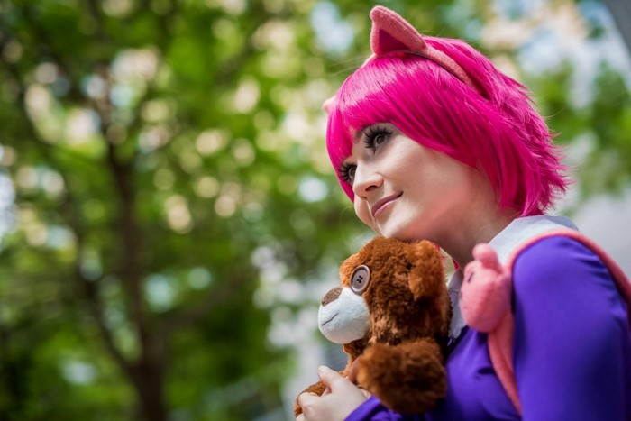Girl in pink wig holding a teddy bear