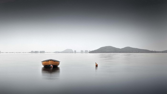 Orange boat on calm water with distant hills