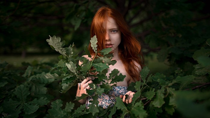 Redhead woman in forest with oak leaves