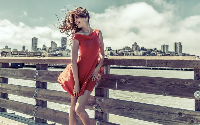 Woman in red dress on a pier with cityscape background