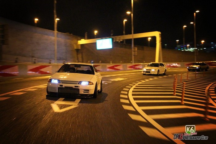 Three cars driving on a road at night