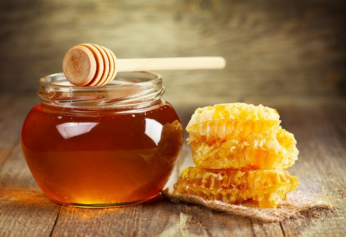 Jar of honey with honeycomb and dipper