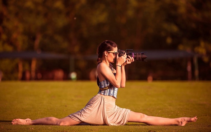 Woman in splits taking a photo with a camera