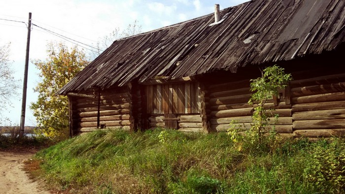 Old wooden barn with a damaged roof in a rural setting
