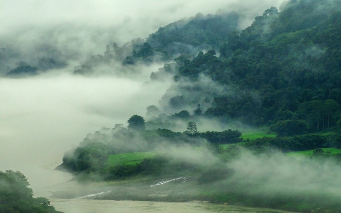 Misty mountains and river in a lush green landscape