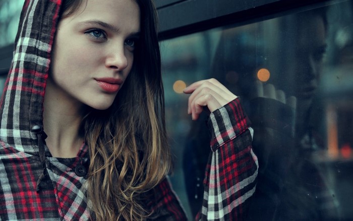 Woman in plaid hoodie looking out a window