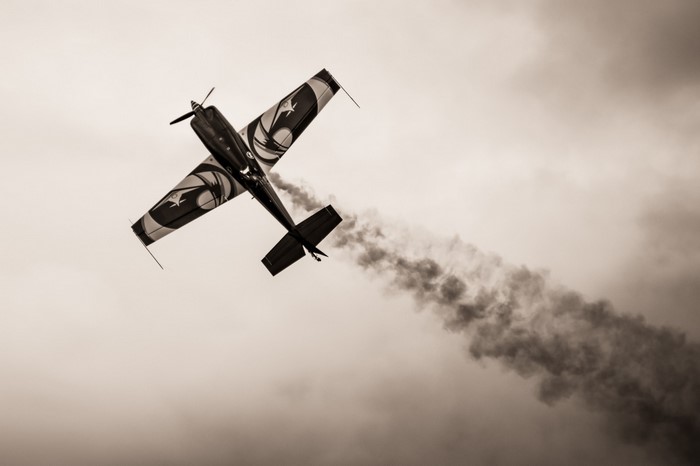 Monochrome airplane performing aerobatics with smoke trail