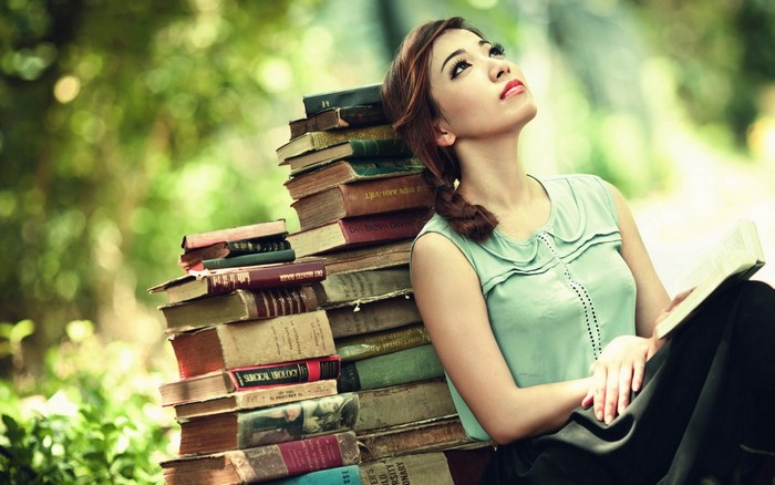 Woman Sitting Outdoors with Books on a Sunny Day