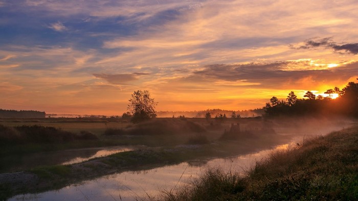 Misty river landscape at sunrise with colorful sky