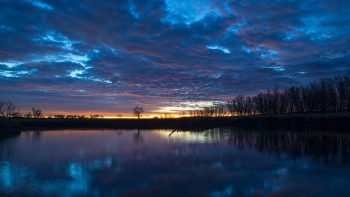 Sunset over a calm lake with dramatic clouds