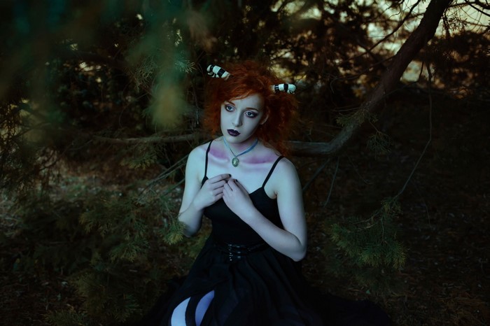 Woman with red hair and striped horns in a black dress