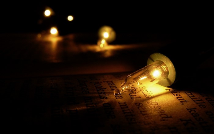 Light bulb illuminating text on a book at night
