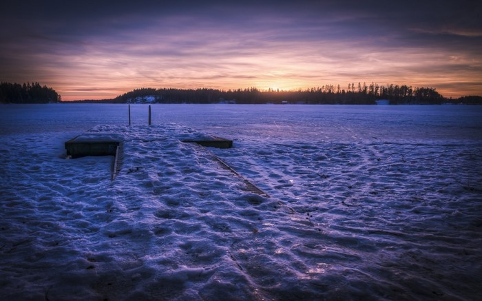 Frozen lake at sunset with wooden dock