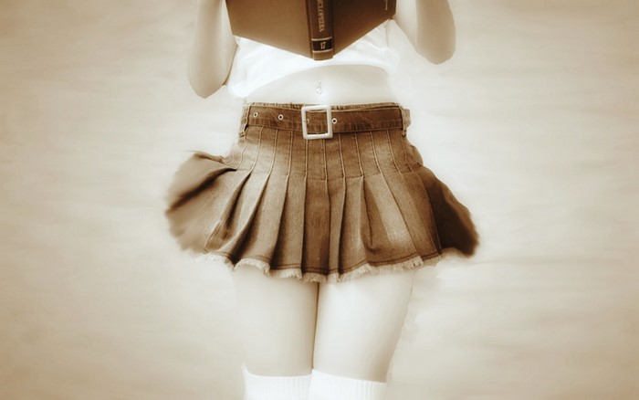 Woman in pleated skirt reading a book