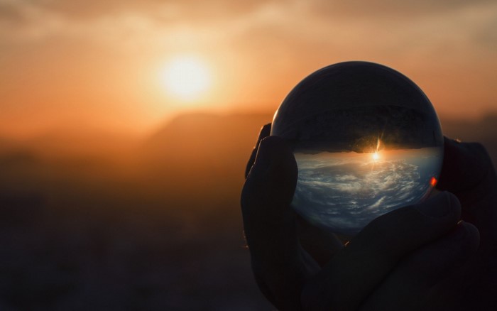 Sunset reflected in a crystal ball held by hands