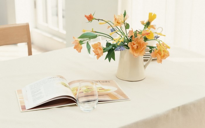 Orange flowers in a vase on a table with a book