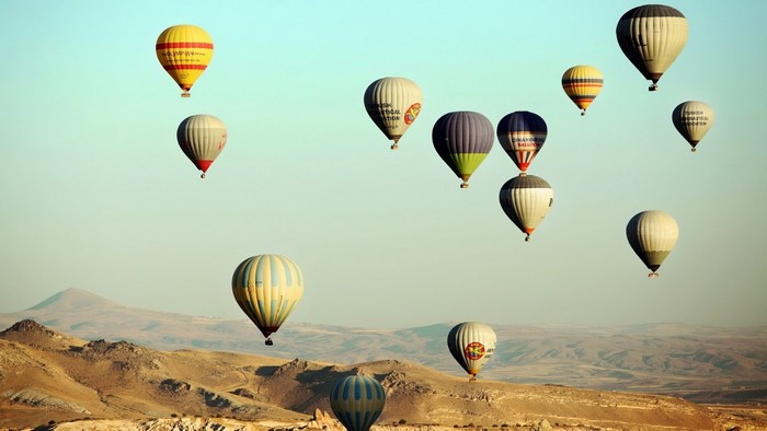 Hot air balloons flying over a desert landscape