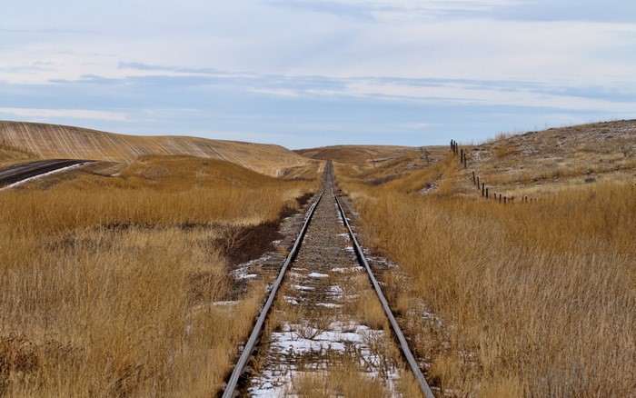 Railroad tracks through a dry, grassy landscape with rolling hills