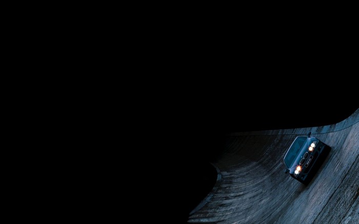 Blue BMW M5 driving on a dark wooden track
