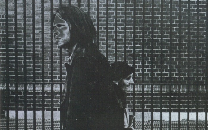 Neil Young and another person in front of a brick wall