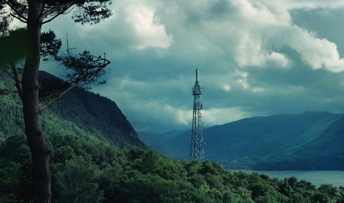 Cell tower on a forested mountain overlooking a lake
