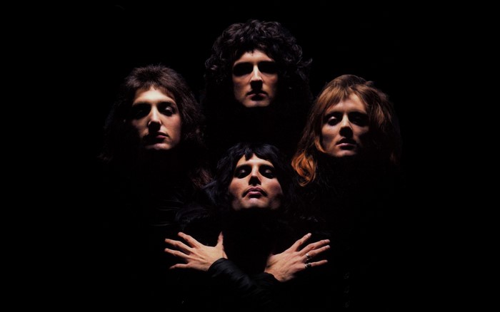 Queen band members in dark lighting