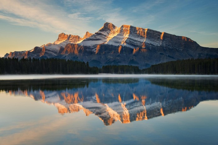 Mountain range reflected in a calm lake at sunrise