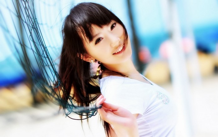Asian woman smiling near a net on a beach