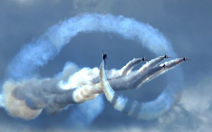Airshow planes performing stunts with smoke trails