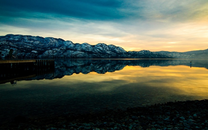 Snowy mountains reflected in a lake at sunset